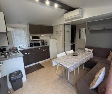 Intérieur séjour avec coin cuisine et canapé du mobil home AU SOLEIL