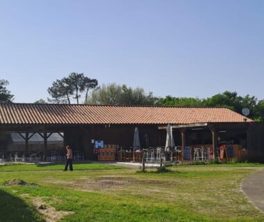 Terrasse couverte avec tables et parasols dans le camping du mobil home Confort Landes 38m2