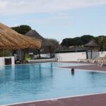 Piscine extérieure avec parasols et transats du mobil home au lac des rêves