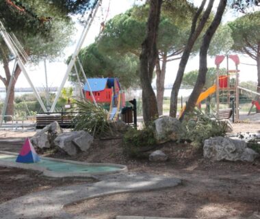 Aire de jeux du camping ombragée avec balançoires et toboggan du mobil home au lac des rêves