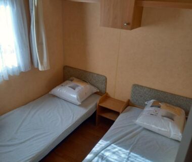 Chambre avec deux lits simples et fenêtre dans le mobil home camping *** les ollivaud