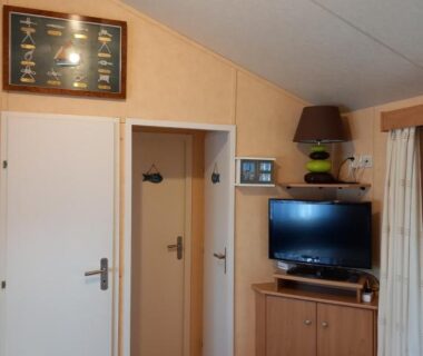 Salon avec télévision et table dans le mobil home du camping Les Ollivaud