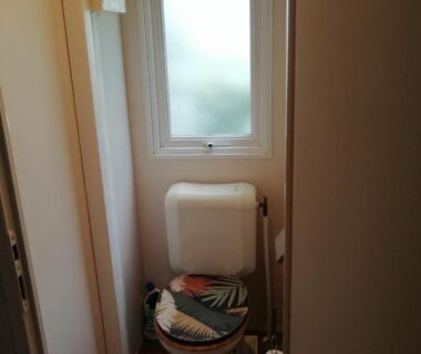 Toilettes étroites avec WC et fenêtre dans le mobil home chez ANIK & ALAIN