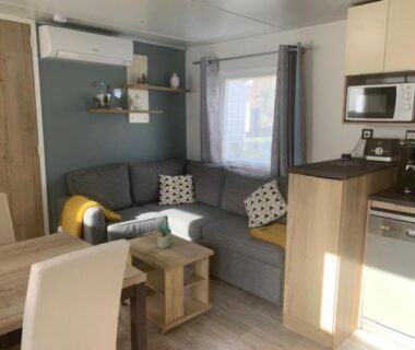Salon avec canapé et kitchenette dans le mobil home chez fred