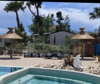 Piscine et solarium avec parasols transats et palmiers au mobil home chill house la jasse