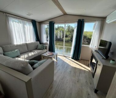 Salon lumineux avec baie vitrée donnant sur un plan d'eau du mobil home climatisé