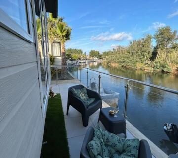 Terrasse au bord du canal avec fauteuils et table dans le mobil home climatisé