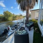 Terrasse au bord de l'eau avec chaises et bateau du mobil home climatisé