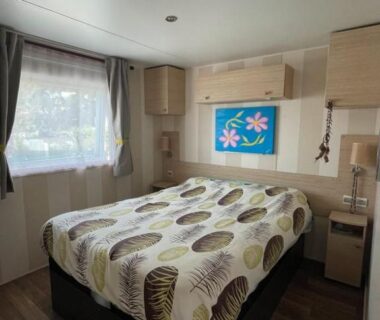 Chambre avec lit double et fenêtre dans le mobil home de luxe