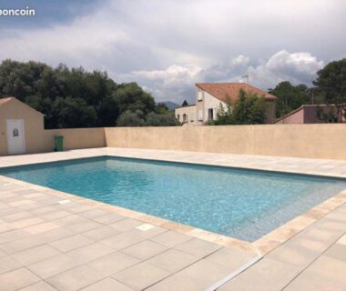Piscine extérieure sur dallage avec muret et maisons en arrière plan du mobil home de luxe