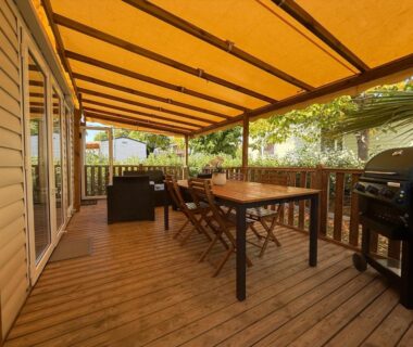 Terrasse couverte en bois avec table et barbecue du mobil home détente et soleil