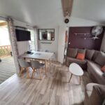 Séjour intérieur avec coin repas et canapé dans le mobil-home Family 6 personnes au Camping Bois Dormant Vendée