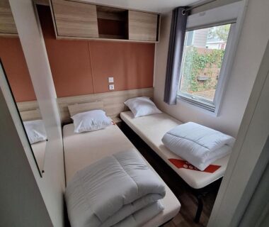 Chambre avec deux lits simples et fenêtre dans le mobil-home family 6 personnes du Camping Bois Dormant Vendée