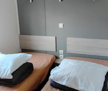 Chambre avec deux lits simples et étagère murale dans le mobil home le castellas Bertrand