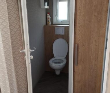 Toilettes intérieures avec placard et fenêtre dans le mobil home l'écrin bleu bougainvilliers