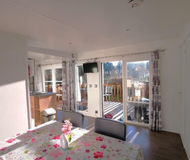 Salon lumineux avec table et baie vitrée dans le mobil home moderne et spacieux