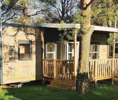 Terrasse en bois sous arbres devant le mobil home moderne et spacieux
