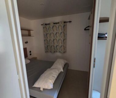 Chambre intérieure avec lit et rideau dans le mobil home soleil et detente