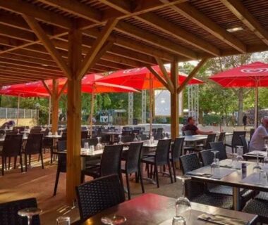Terrasse couverte avec tables et parasols rouges du mobil home tout confort 6 personnes climatisé au pied du Luberon