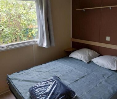 Chambre avec lit et fenêtre donnant sur végétation extérieure du mobil home 6 personnes climatisé au pied du Luberon