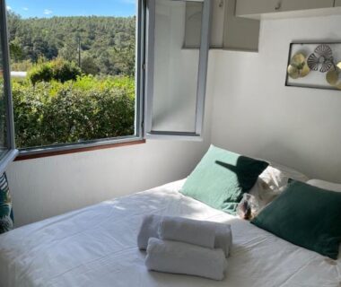 Chambre avec lit serviettes et fenêtre ouverte sur la colline dans le mobile home dans un coin de paradis