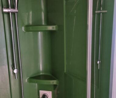 Cabine de douche verte avec pommeau et étagère dans le mobilhome au domaine des iscles emplacement 137