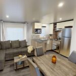 Séjour lumineux avec canapé et cuisine équipée dans le mobilhome neuf