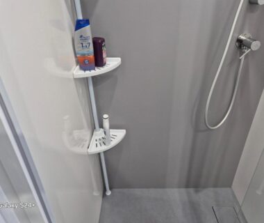 Cabine de douche avec pommeau et étagère à produits dans le mobilhome neuf