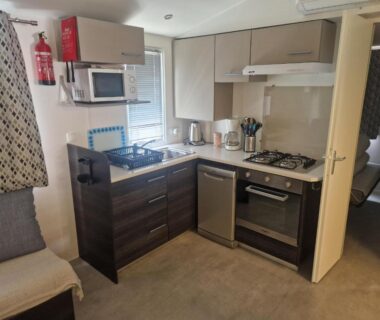 Cuisine équipée avec cuisinière micro-ondes et bouilloire dans le mobil-home tout confort