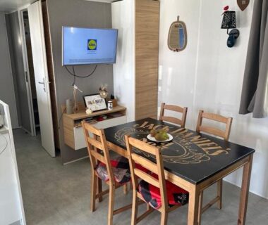 Intérieur coin repas avec table et télévision dans le mobilhomme 3 Chambres avec piscine