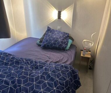 Chambre avec lit simple, applique murale et chevet dans le mobilhomme 3 Chambres avec piscine