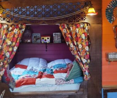 Intérieur de roulotte avec lit rideaux et coussins colorés dans la roulotte Tipergwendiou