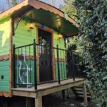 Dans un jardin arboré roulotte verte sur pilotis la roulotte Tipergwendiou