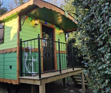 Dans un jardin arboré roulotte verte sur pilotis la roulotte Tipergwendiou
