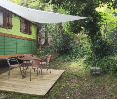Terrasse en bois ombragée dans un jardin devant la roulotte Tipergwendiou