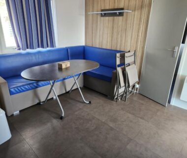 Coin repas intérieur avec banquette bleue table pliante et chaises empilées dans le sol a gogo 3 ch