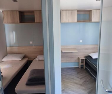 Intérieur avec lits simples et rangements dans le superbe mobil home 6/8 pers clim sans vis a vis