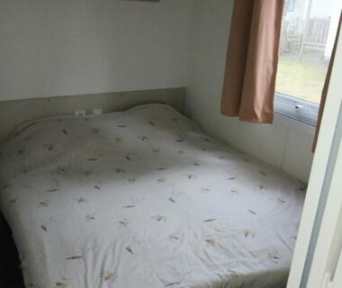 Chambre avec lit double et fenêtre dans le sweet mobil-home