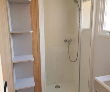 Salle de bain avec cabine de douche et étagères au camping tony vacances