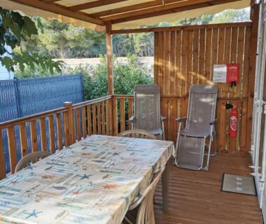 Terrasse couverte avec table chaises et deux transats du camping tony vacances