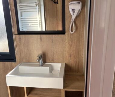 Salle de bains avec lavabo miroir sèche-cheveux sur panneau bois dans le camping zoubidou